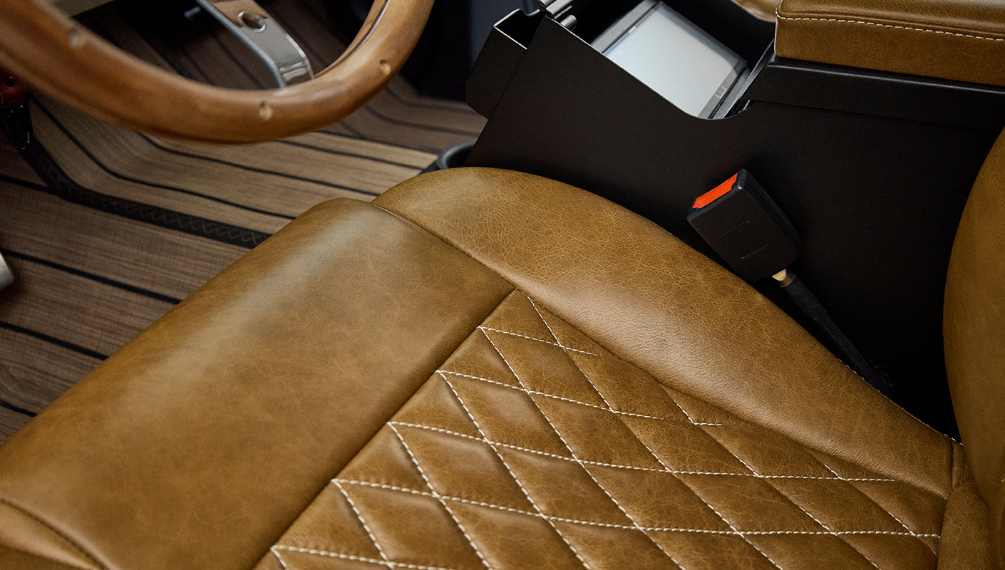 Brown leather car seat with diamond stitching and black seatbelt buckle in console area