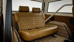 Rear brown leather bench seat with diamond stitching inside classic vehicle near large windows