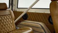 Brown quilted leather door panel and speaker behind rear seat with beige roll bar inside vehicle