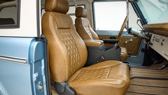Two brown leather front seats with diamond stitching and blue vehicle door visible