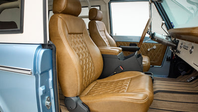 Two brown leather front seats with diamond stitching and blue vehicle door visible