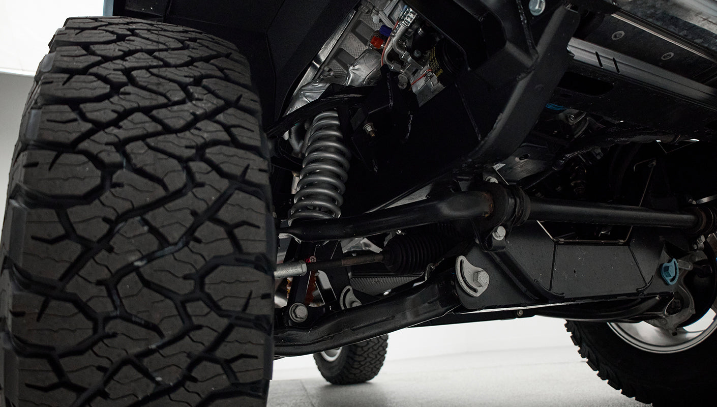 Close-up of Classic Ford Bronco suspension and large off-road tire showing coil spring and control arm