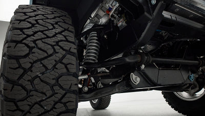 Close-up of Classic Ford Bronco suspension and large off-road tire showing coil spring and control arm