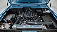 Front view under raised hood showing Classic Ford Bronco engine and surrounding components in blue engine bay