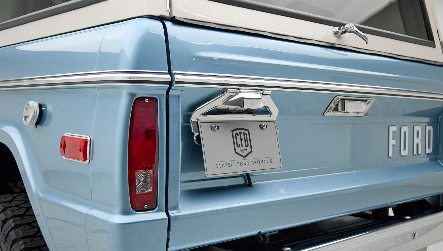 Rear corner of Classic Ford Bronco in blue with tail light, license plate, and gas cap visible