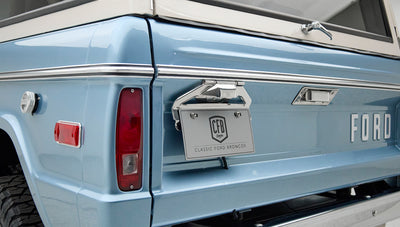Rear corner of Classic Ford Bronco in blue with tail light, license plate, and gas cap visible