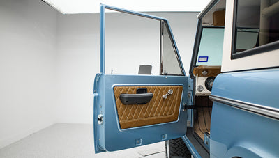 Open driver-side door of Classic Ford Bronco revealing quilted tan door panel and part of interior