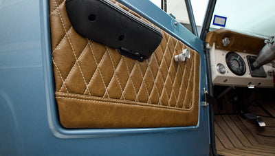 Close-up of blue door panel inside Classic Ford Bronco with quilted brown leather and black door handle
