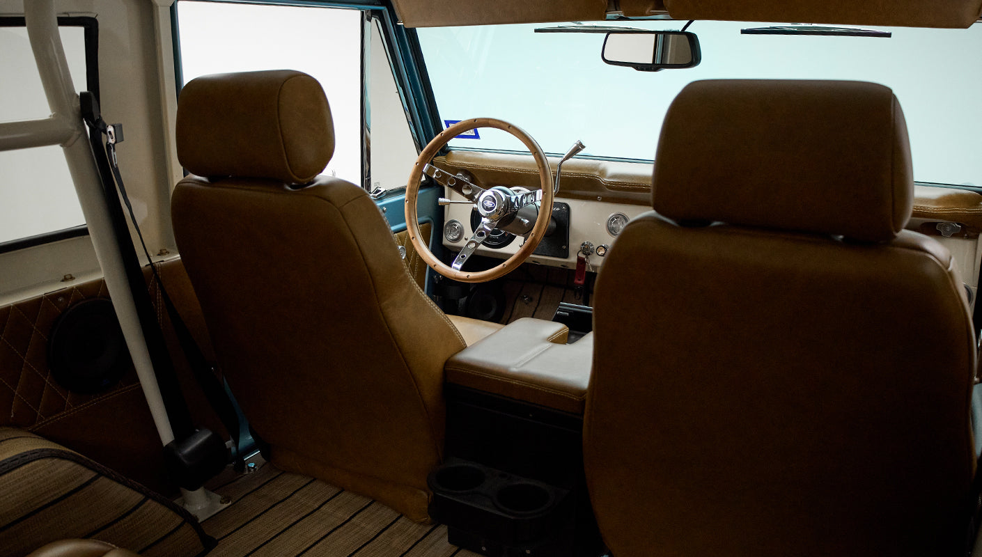 Classic Ford Bronco front seats and dashboard with wooden steering wheel and tan upholstery