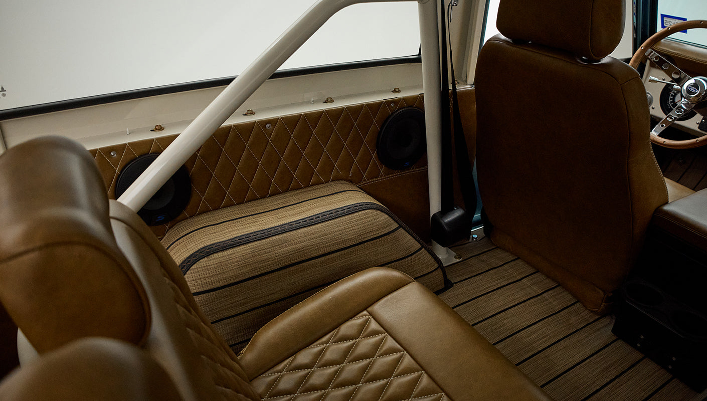 Rear seating area of Classic Ford Bronco with tan upholstery and roll bar