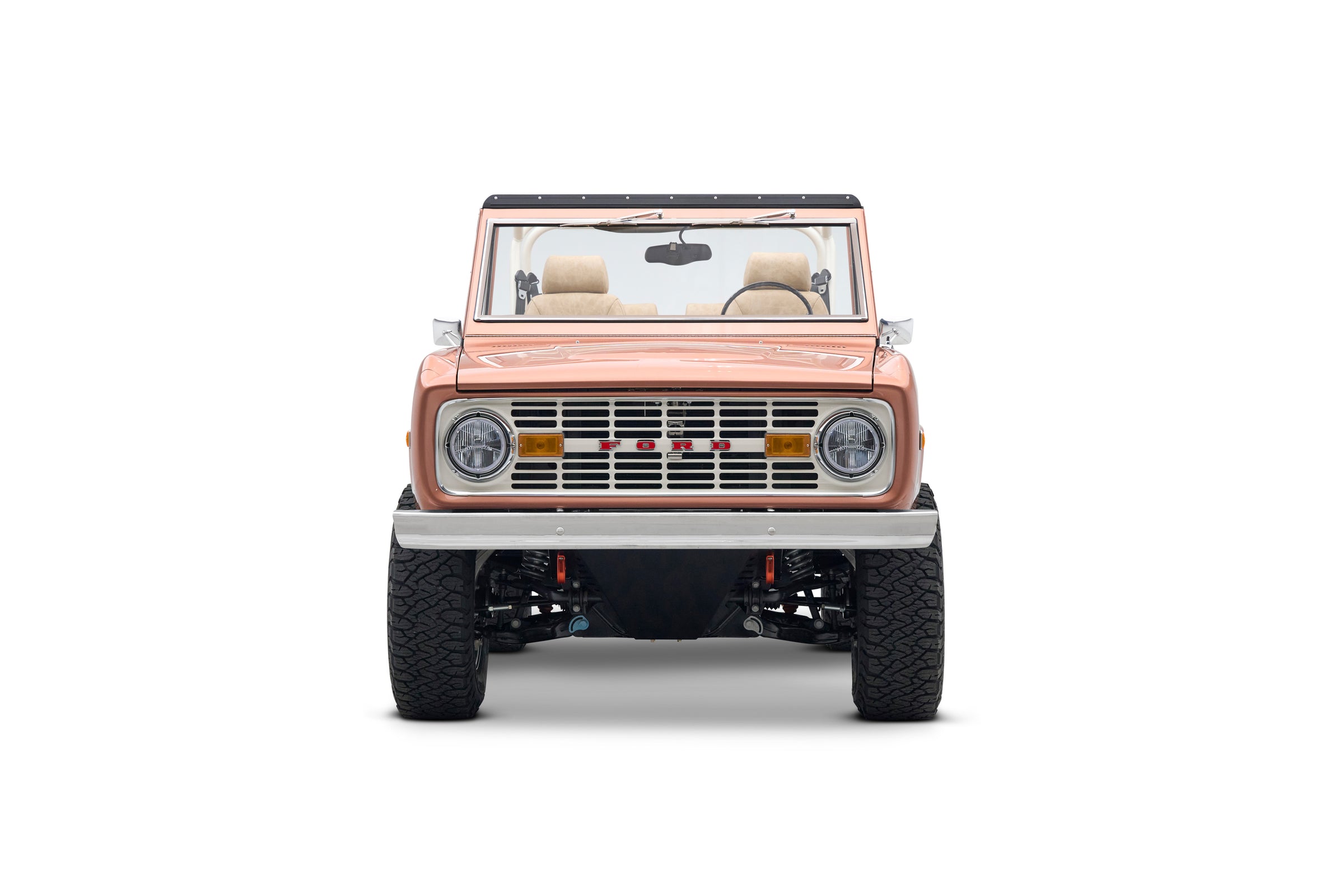 Front view of Classic Ford Bronco in peach color with beige seats and a white roll cage