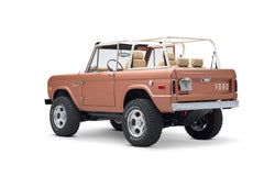 Rear side angle of Classic Ford Bronco showing off-road tires, peach body, and white roll cage