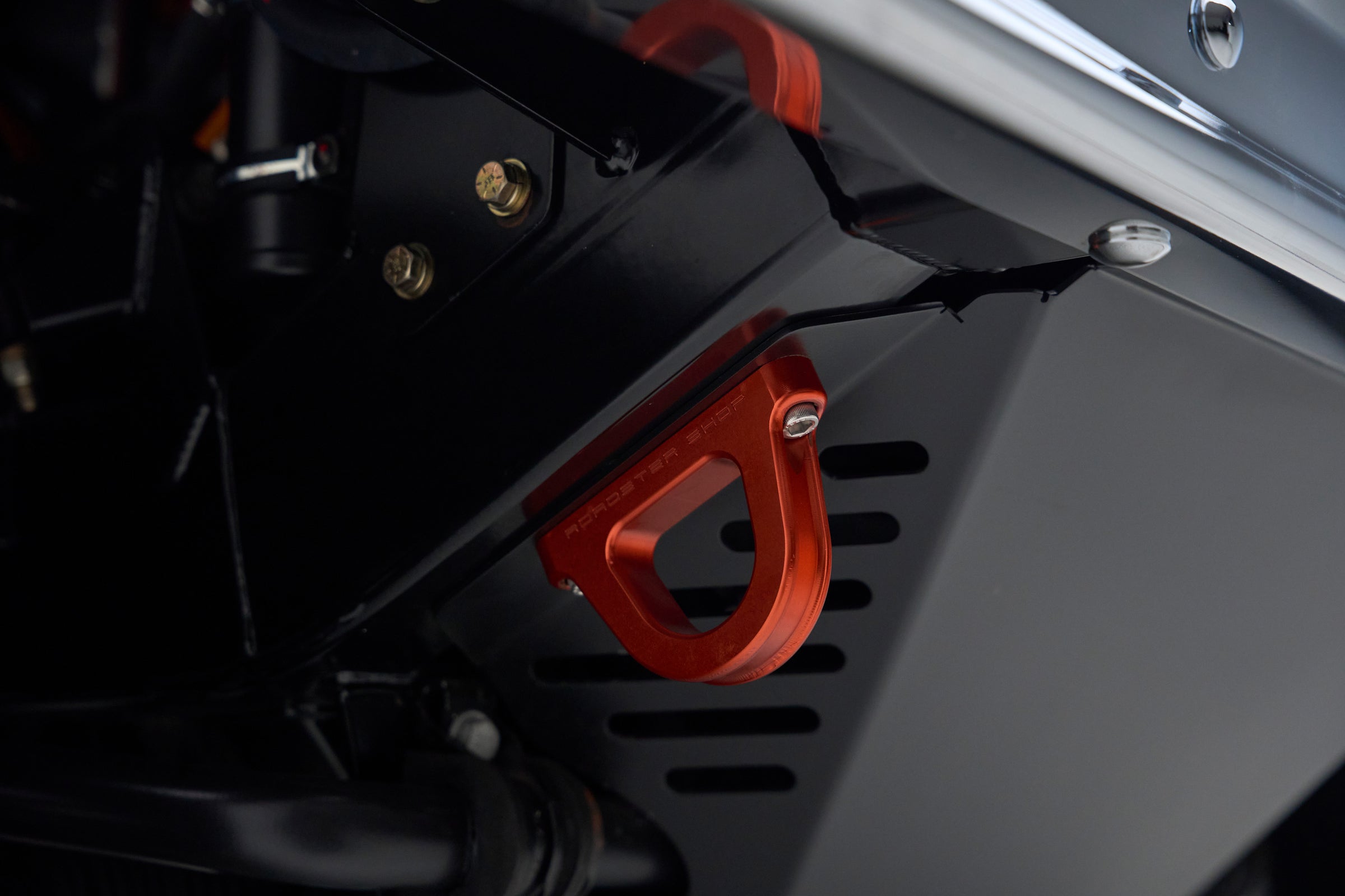 Red metal component mounted under the vehicle, part of Classic Ford Bronco's suspension or chassis