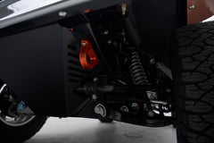Suspension system and wheel well of a Classic Ford Bronco with black and orange parts.