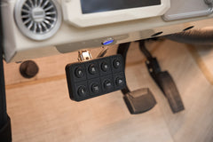 Electronic gear selector panel and pedals inside a Classic Ford Bronco with wood-like floor.