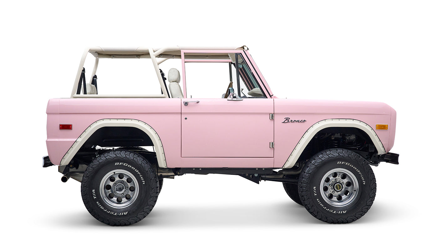 Side profile of Classic Ford Bronco in pink with white wheel arches and black tires