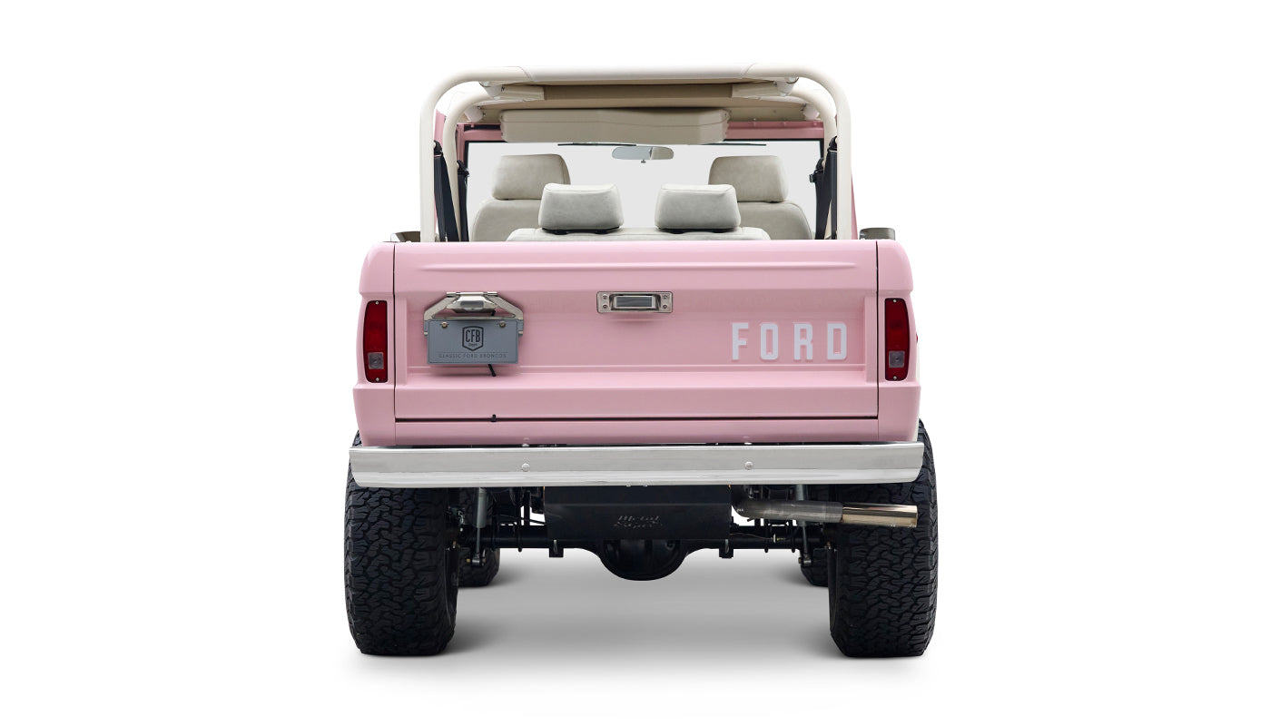 Rear view of Classic Ford Bronco in pink with white interior seats and visible suspension