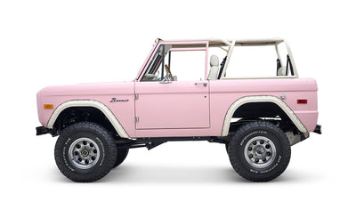 Side profile of pink Classic Ford Bronco with white roll cage and large BFGoodrich tires