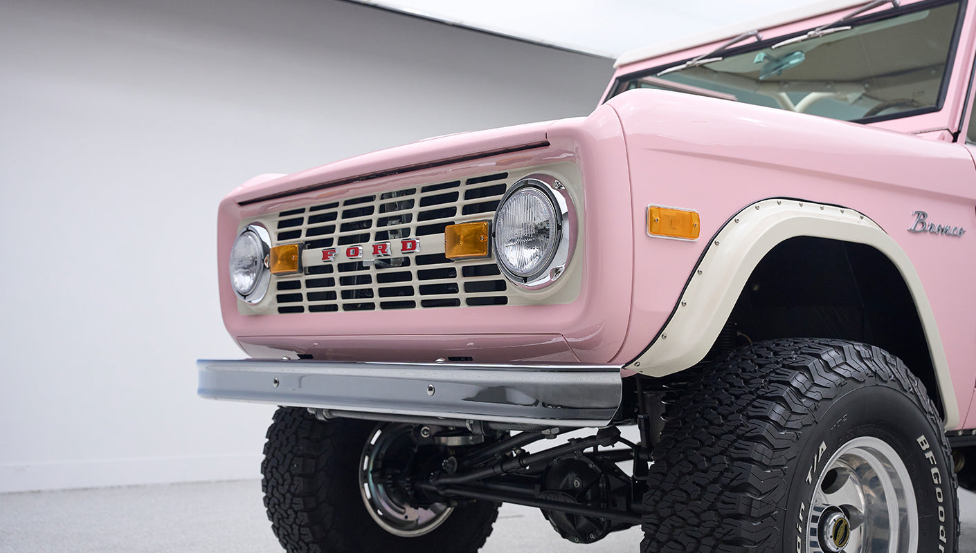 Close-up view of front grille and headlights of pink Classic Ford Bronco