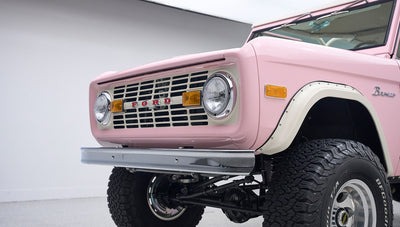 Close-up view of front grille and headlights of pink Classic Ford Bronco