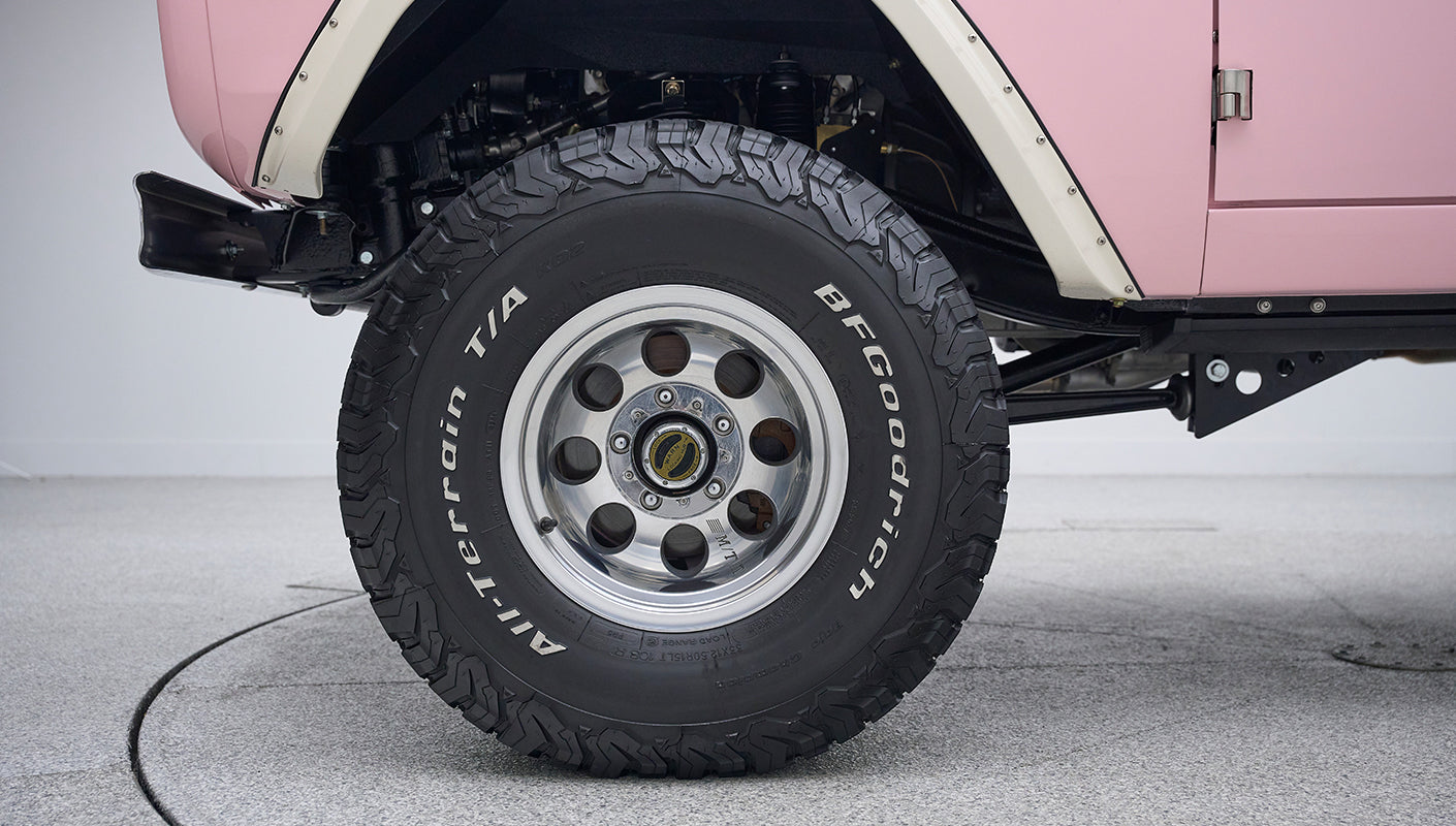 Close-up of BFGoodrich All-Terrain T/A tire and shiny multi-hole aluminum wheel on Classic Ford Bronco