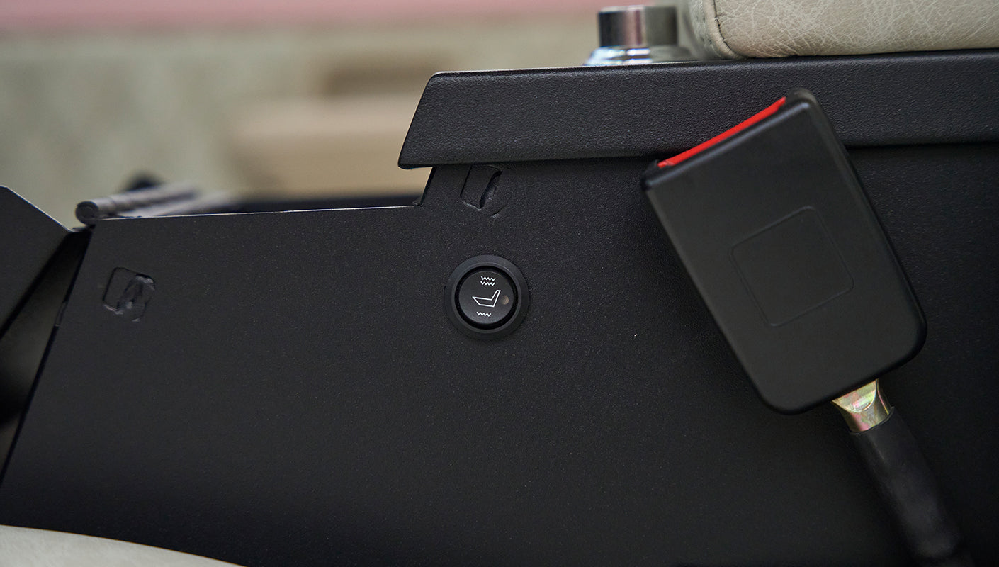 Black control panel featuring a heated seat button and a seatbelt latch in a Classic Ford Bronco