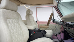 Driver side interior view of Classic Ford Bronco with beige seats and wooden steering wheel