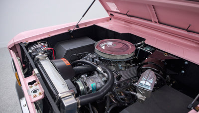 Detailed view of engine from front left side in pink Classic Ford Bronco with hood open