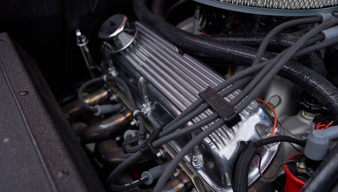 Close-up of polished engine valve cover and spark plug wires in pink Classic Ford Bronco