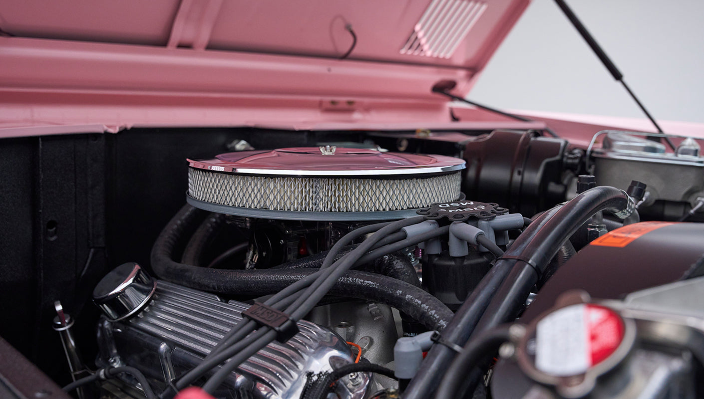 Side view of air filter and ignition wires in engine bay of pink Classic Ford Bronco