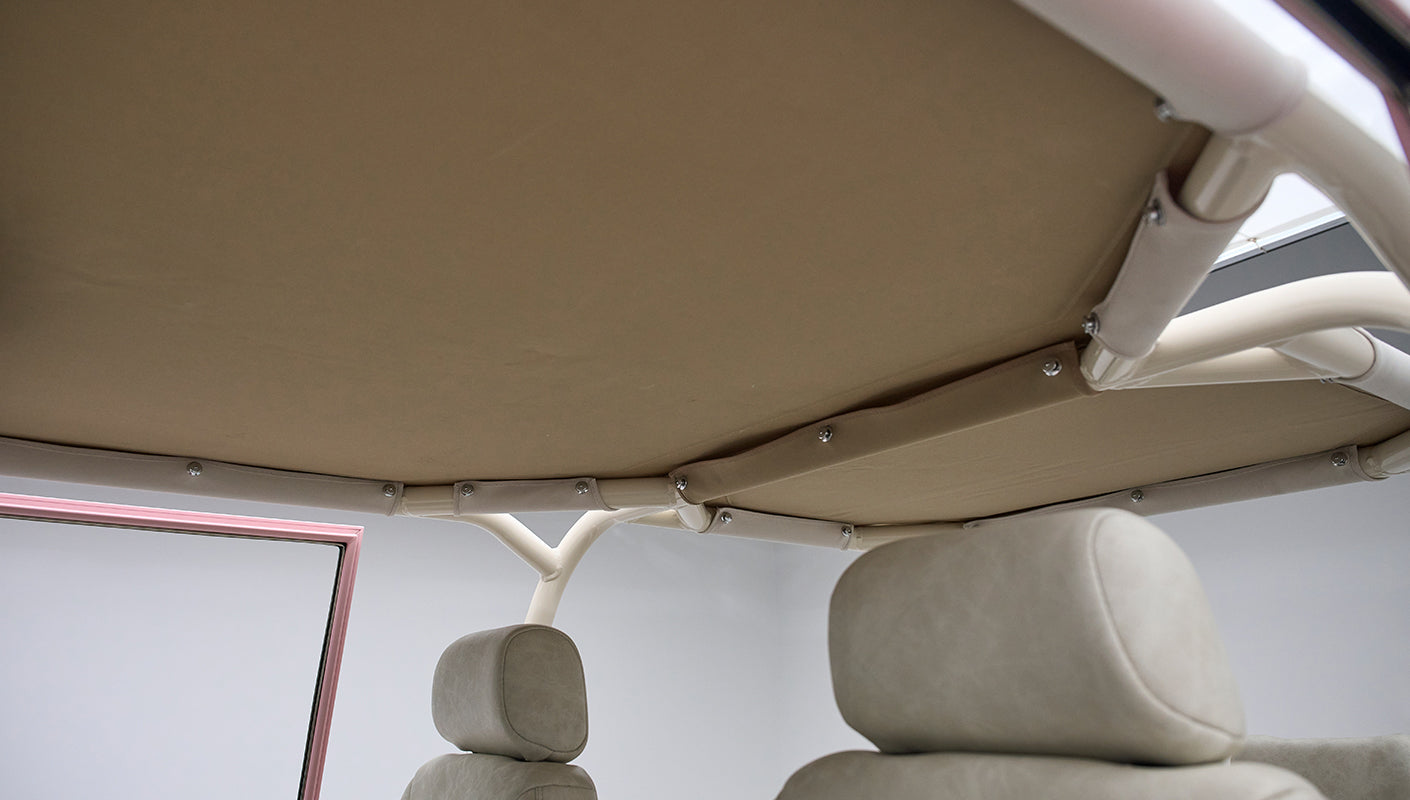 View of beige fabric roof frame and upholstery inside pink Classic Ford Bronco