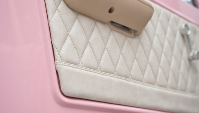 Close-up detail of quilted cream upholstery on the door of a pink Classic Ford Bronco.