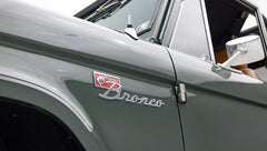Close-up of Classic Ford Bronco front left fender emblem reading 'Sport Bronco' with green paint.