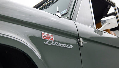 Close-up of Classic Ford Bronco front left fender emblem reading 'Sport Bronco' with green paint.