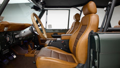 Classic Ford Bronco front seats with brown leather and woven fabric upholstery inside dark green vehicle