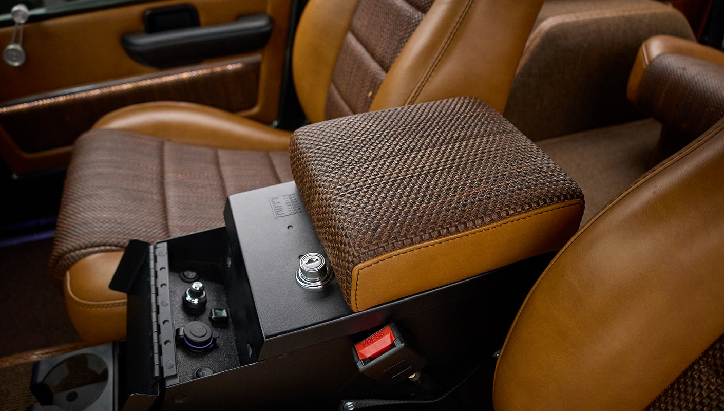 Classic Ford Bronco center console armrest covered in brown woven fabric and leather with lock mechanism