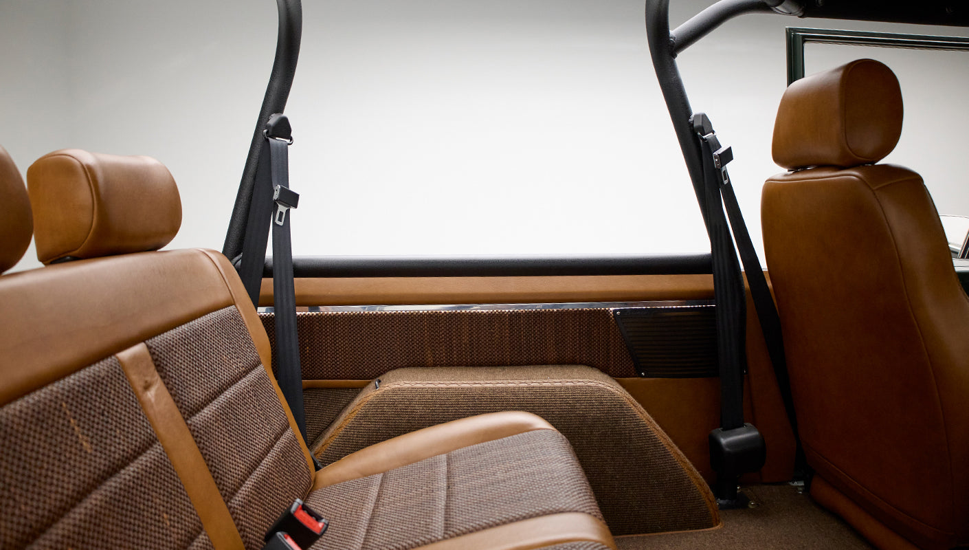 Rear interior seating and roll bar of Classic Ford Bronco with tan and brown upholstery