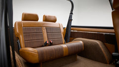 Back seat of Classic Ford Bronco with tan and brown upholstery and seat belts