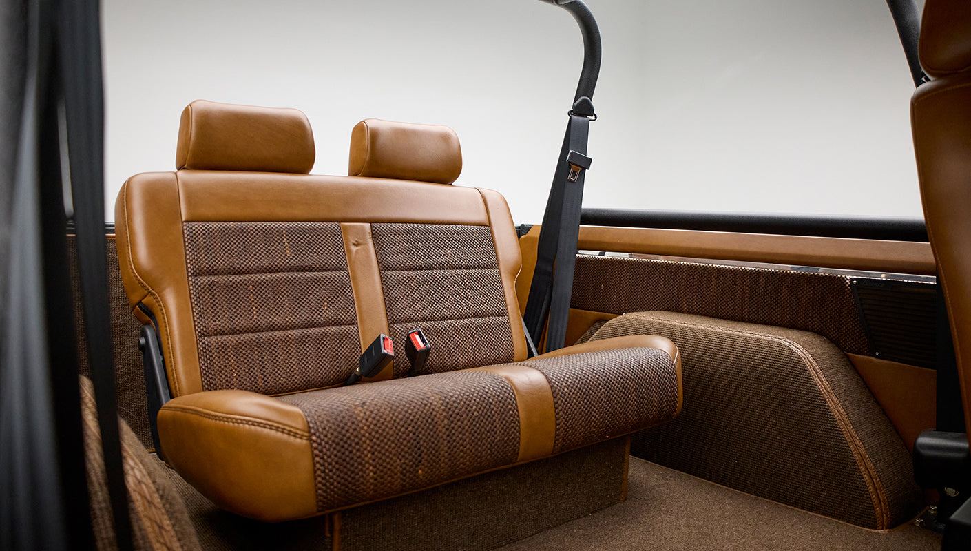 Back seat of Classic Ford Bronco with tan and brown upholstery and seat belts