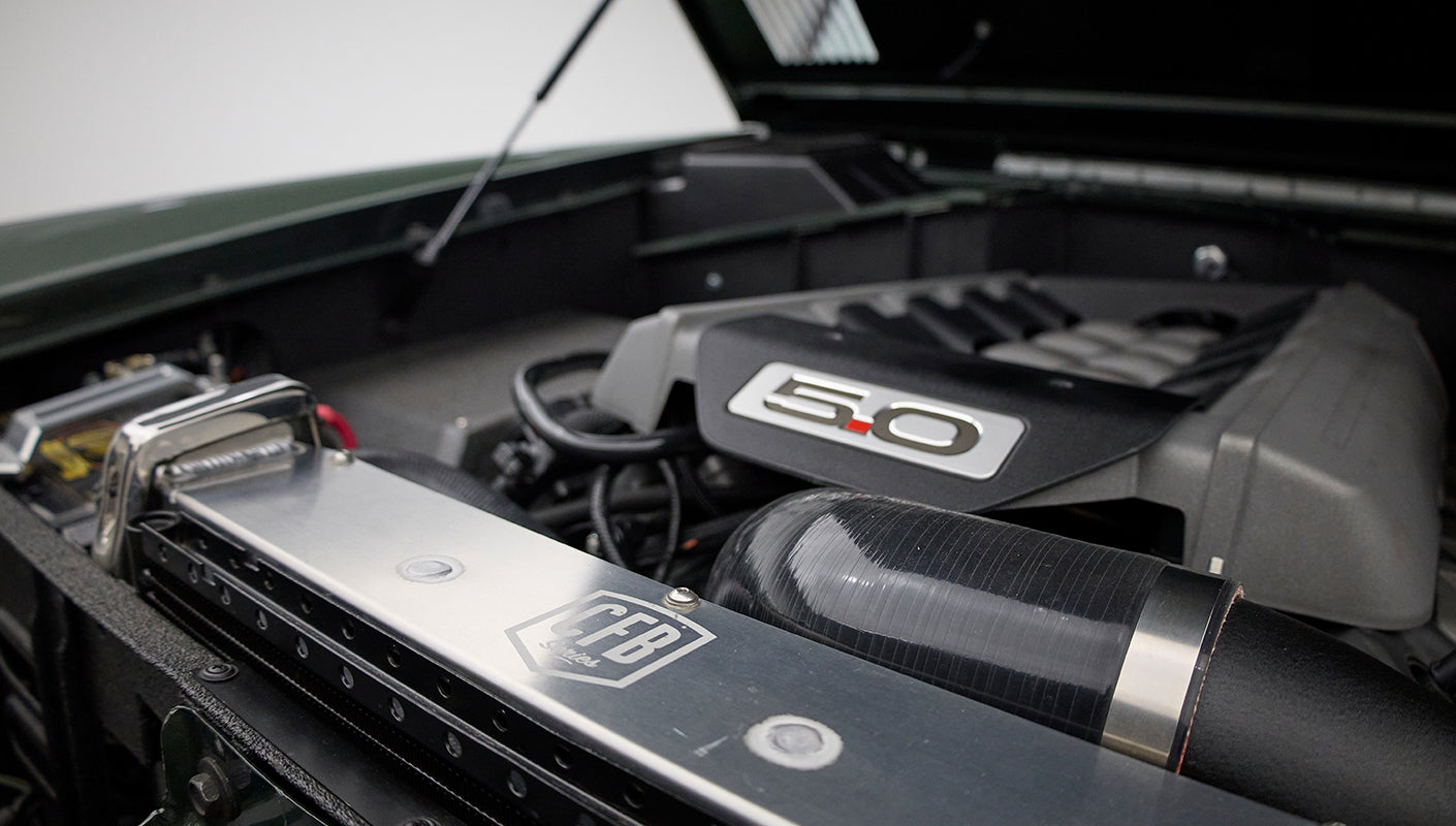 Side view of Classic Ford Bronco engine bay featuring 5.0 emblem and air intake hose