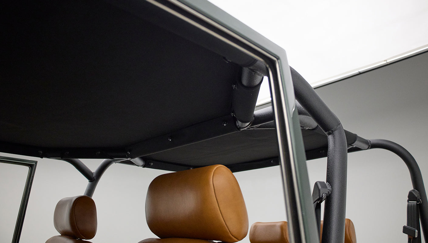 View inside Classic Ford Bronco showing black roll cage and tan leather headrest
