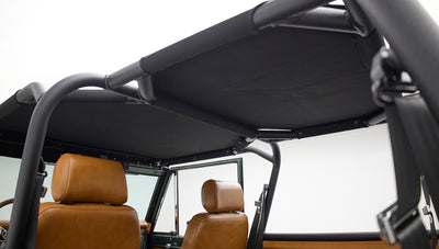 Black roll cage and tan leather seats seen through side of Classic Ford Bronco
