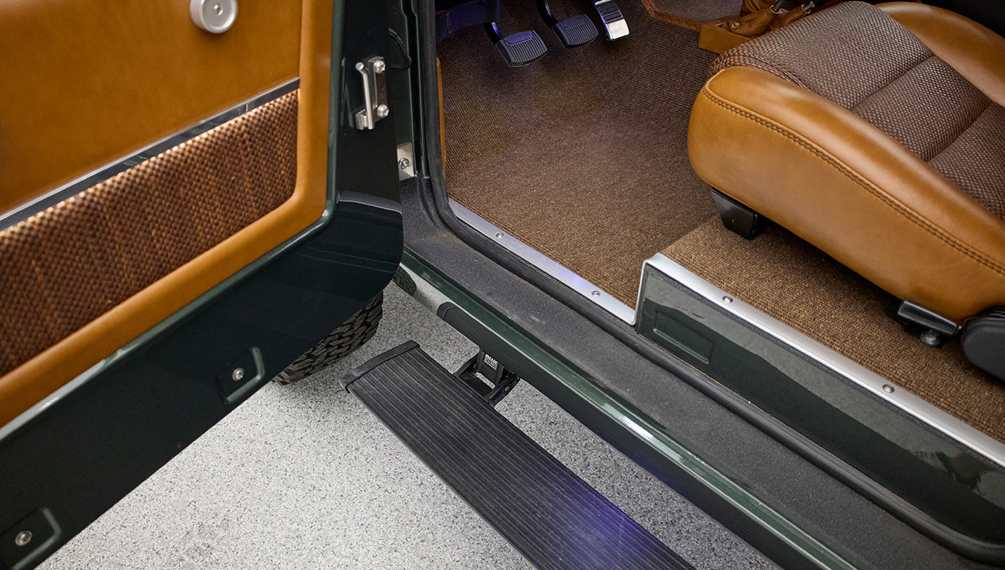 Side step, door edge, and brown textured carpet floor visible inside Classic Ford Bronco