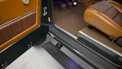 Side step, door edge, and brown textured carpet floor visible inside Classic Ford Bronco