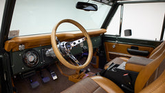 Complete front interior showing steering wheel, instrument cluster, and brown textured seats in Classic Ford Bronco