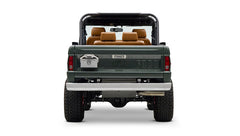 Rear view of dark green Classic Ford Bronco with open cargo bed, chrome bumper and large off-road tires on white background