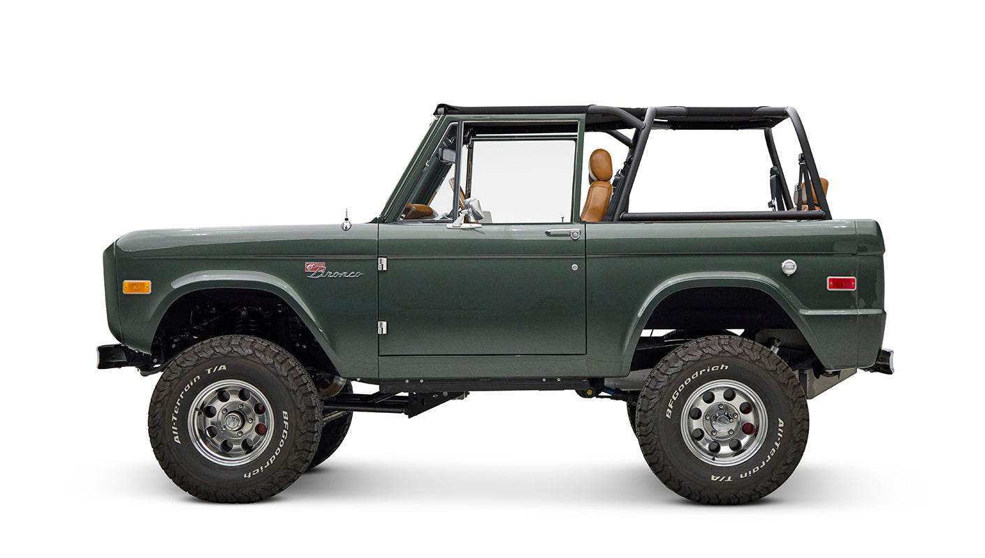 Classic Ford Bronco dark green side profile with open top and chrome wheels on white background.