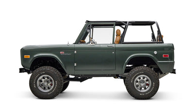 Classic Ford Bronco dark green side profile with open top and chrome wheels on white background.
