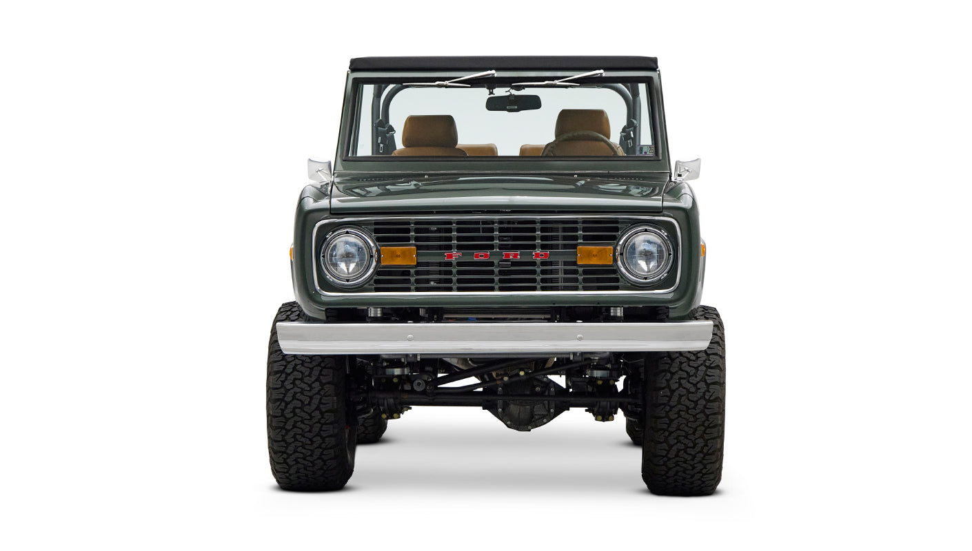 Classic Ford Bronco dark green front view with chrome bumper, grill, and amber turn signals.