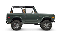 Classic Ford Bronco dark green side profile from right with chrome wheels and open top.